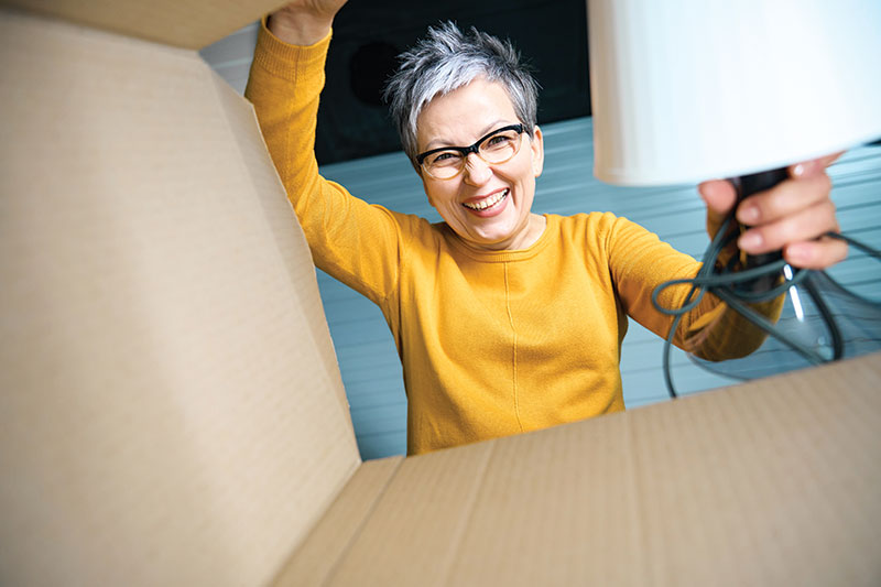 senior woman packing lamp into a box photo